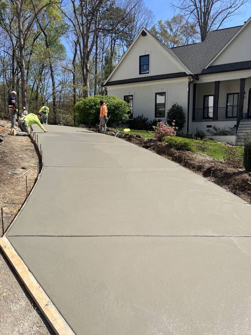 Long new concrete driveway up to a white house
