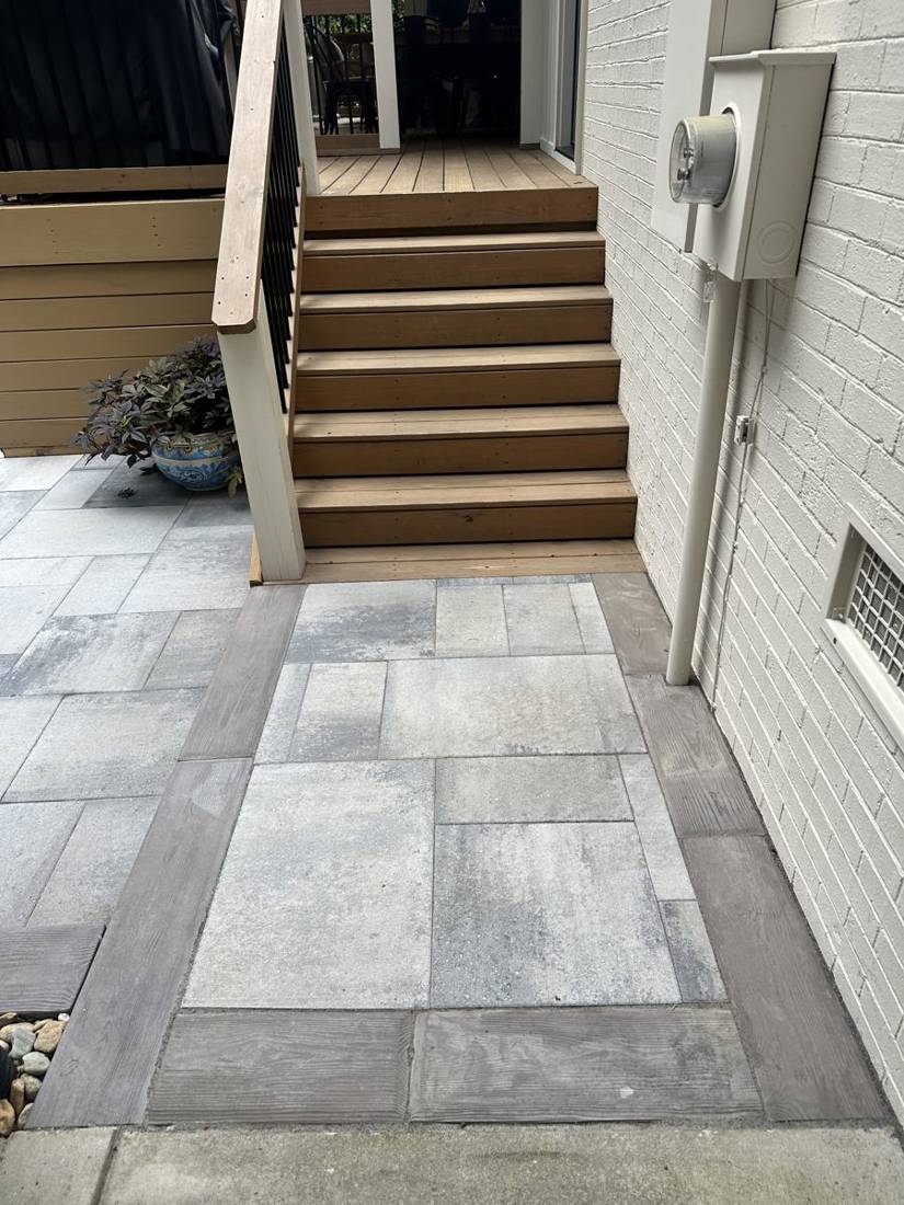 Large-format paver landing with plank-style border at deck stairs