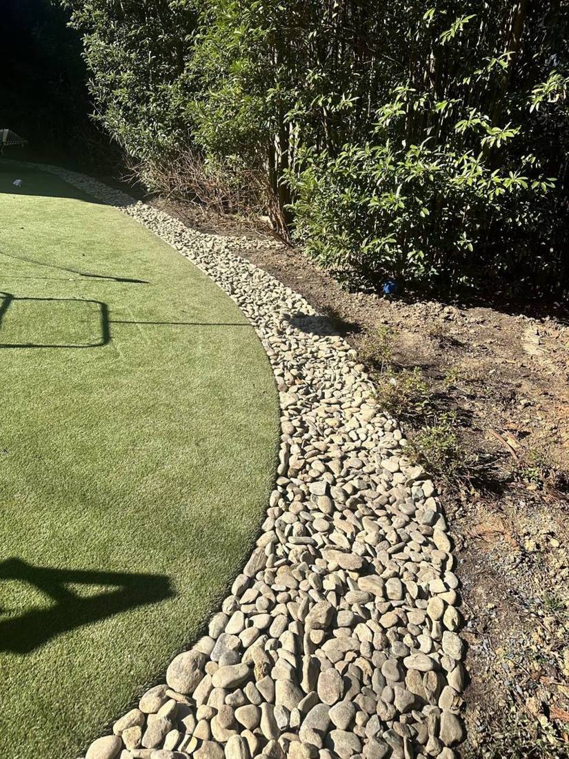 River rock border along artificial turf