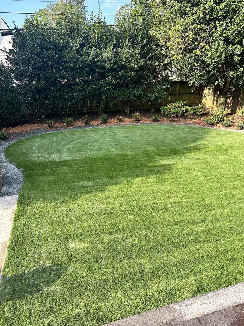 Curved artificial turf lawn with gravel edge and new plantings